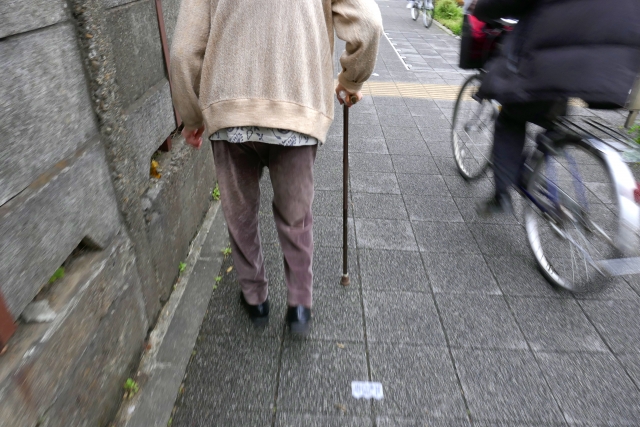 歩行補助杖を使用する老人